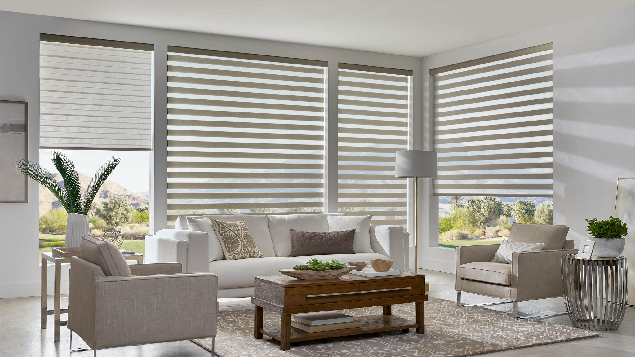 Four motorized gray banded shades in a brightly lit living room.